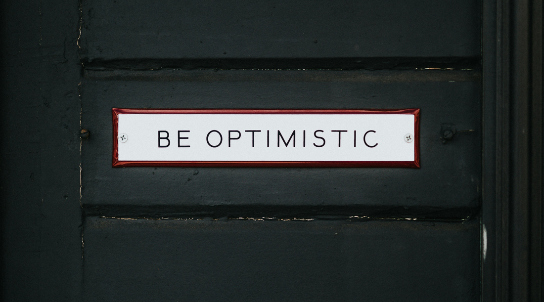 Be optimistic slogan posted in a black door