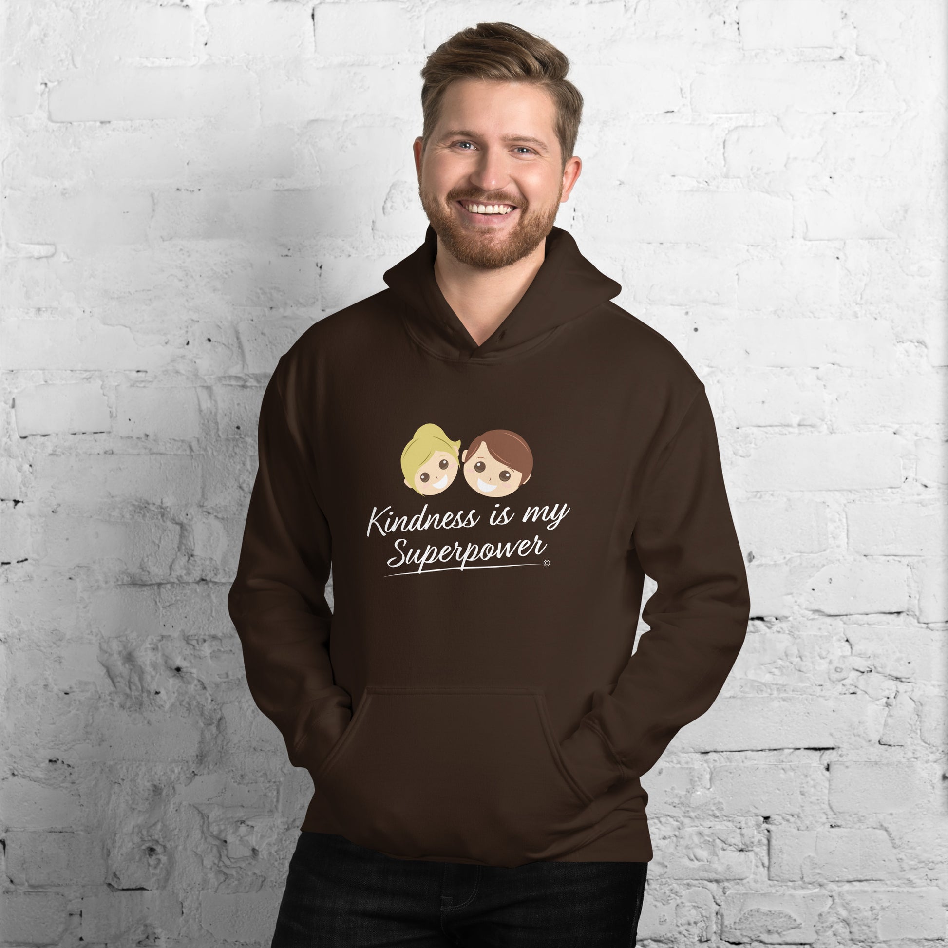A smiling man showcasing a comfortable unisex hoodie in chocolate brown, featuring the uplifting quote 'Kindness is my Superpower' in bold lettering.